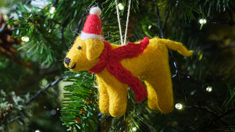 A felt Christmas tree decoration of a Golden Labrador in a red hat and scarf